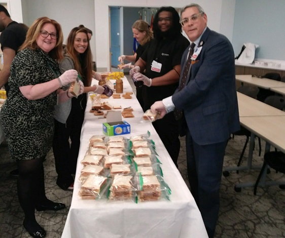 Group of Cooper employees making and packing peanut butter and jelly sandwiches.