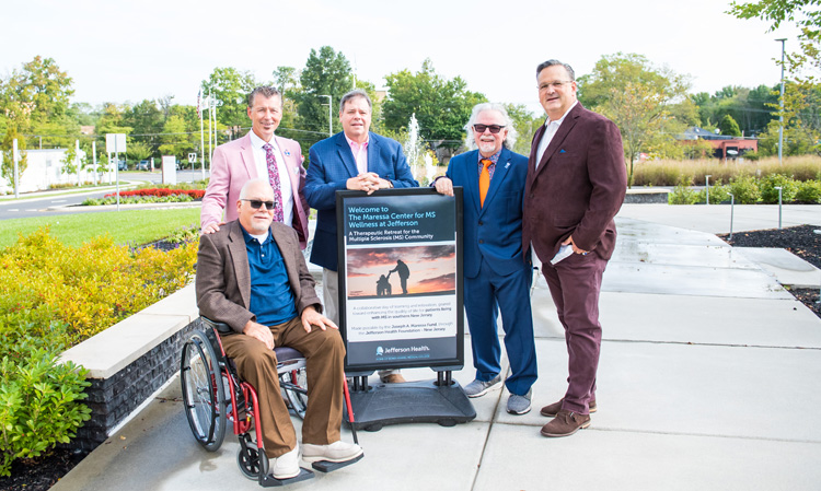 Group of gentlemen standing by sign for The Maressa Center for MS Wellness.