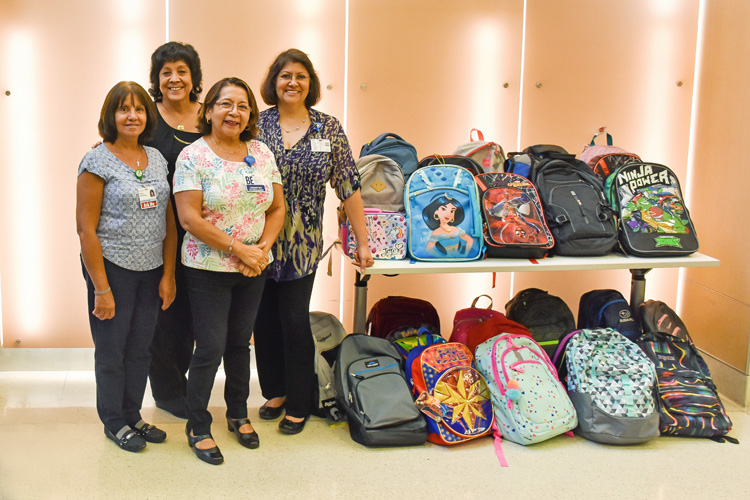 Penn Medicine Princeton Health staff standing by collection of school backpacks.