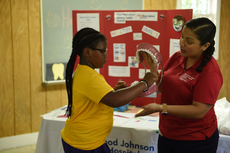 RWJBarnabas Somerset employee teaching a student with a model of the human mouth.