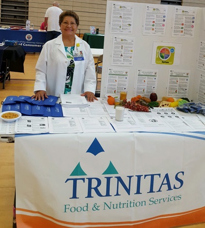 Dietitian Julia Sotomayor posing behind informational table at Julia Health Fair.