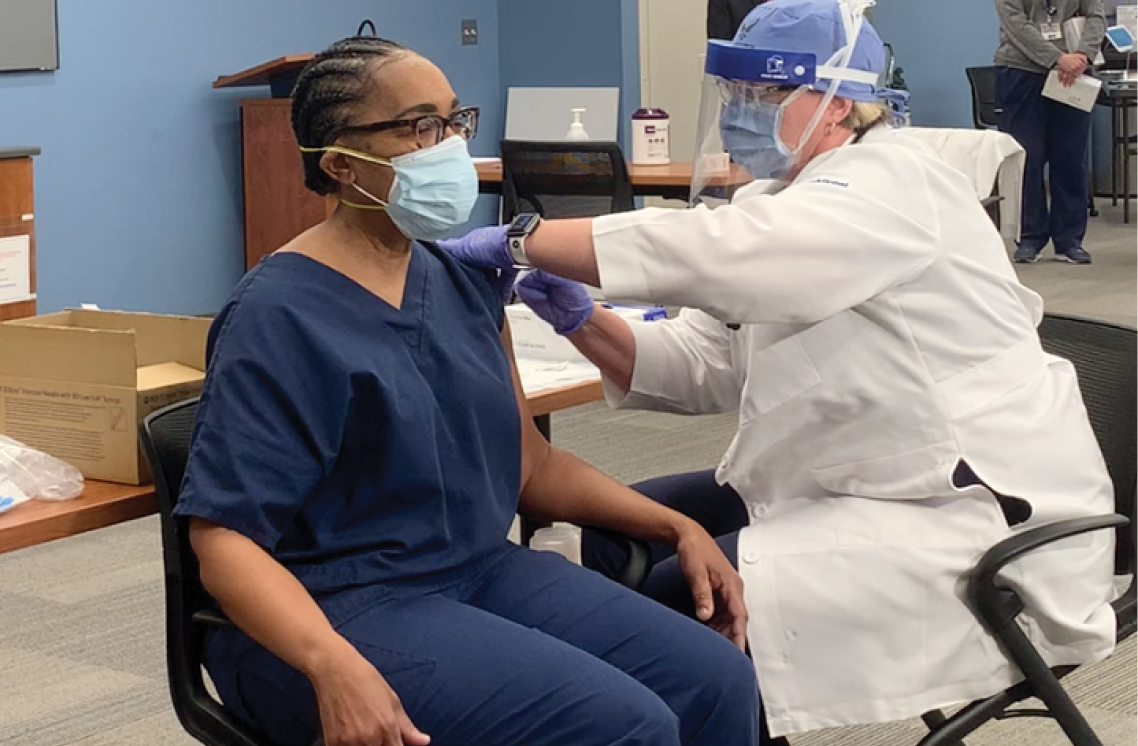 Female healthcare worker administering vaccine to a female patient.