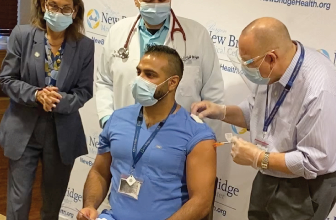 Male healthcare worker administering vaccine to a male patient.