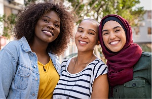 Three girls standing together smiling.