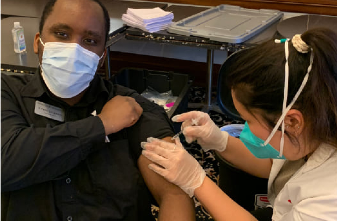 Female healthcare worker administering vaccine on male patient.